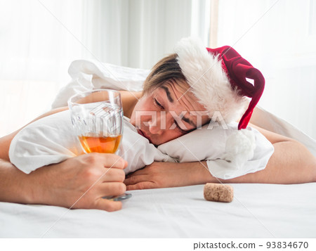 Man in Santa hat is trying to freshen the nip after alco party. He is suffering of headache after New Year or Christmas celebration. Heavy morning. Alcohol withdrawal. Worst hangover. 93834670