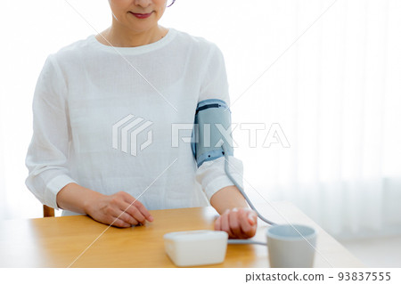 Middle-aged woman in the living room Sphygmomanometer Middle-aged woman in the living room Sphygmomanometer 93837555