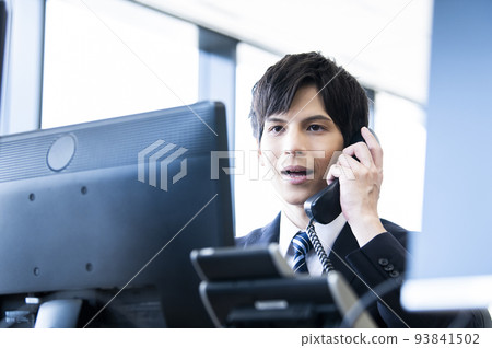 Young male employee making a phone call in the office 93841502