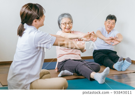 Senior men and women exercising at day service and physical therapist Senior men and women exercising at day service and physical therapist 93843011