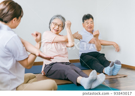 Senior men and women stretching and a trainer woman 93843017