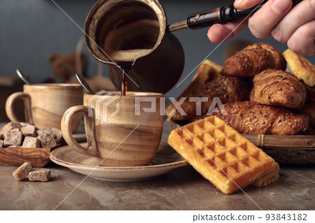 Breakfast with black coffee and fresh pastries. 93843182