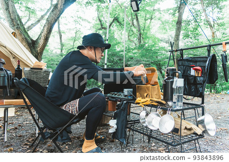 日本男露營者在營地做飯（調味） 93843896
