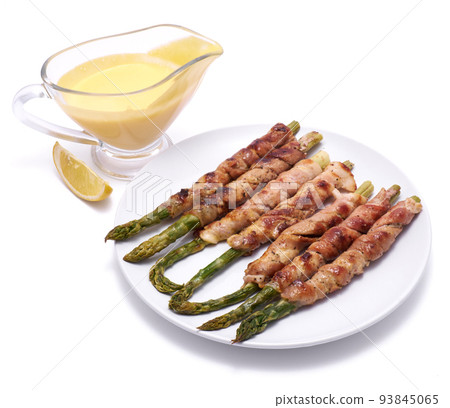 Healthy food - Asparagus wrapped with bacon and spices on a plate isolated on white background Healthy food - Asparagus wrapped with bacon and spices on a plate isolated on white background 93845065