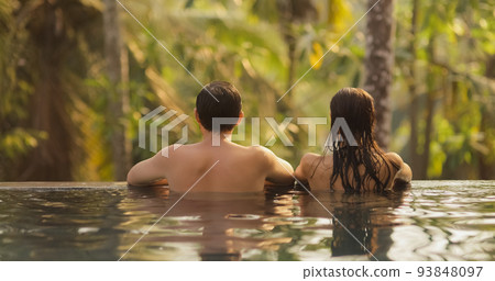 Couple in Love Together in Infinity Swimming Pool Outdoors During Tropical Vacation Couple in Love Together in Infinity Swimming Pool Outdoors During Tropical Vacation 93848097