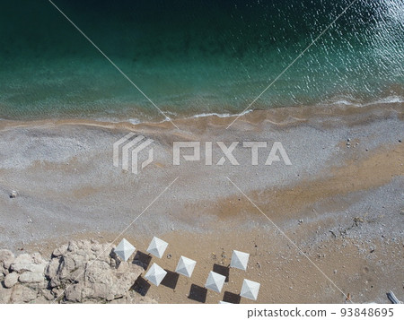 Aerial view from above on azure sea and pink pebbles beach. Small waves on cristal clear water surface in motion blur. Summer ocean sea beach background. Nobody. Holiday, vacation and travel concept Aerial view from above on azure sea and pink pebbles beach. Small waves on cristal clear water surface in motion blur. Summer ocean sea beach background. Nobody. Holiday, vacation and travel concept 93848695