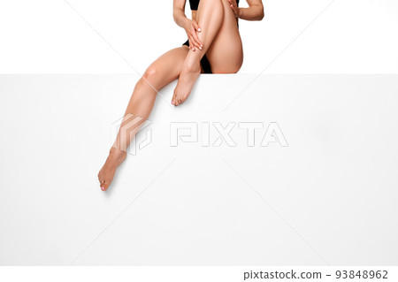 woman with slim legs sitting on white bench. 93848962