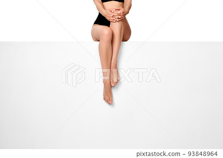 woman with slim legs sitting on white bench. woman with slim legs sitting on white bench. 93848964