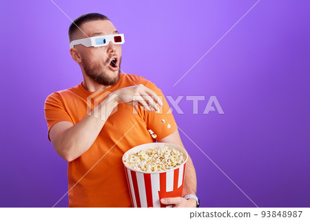 Young caucasian man in 3d glasses eating popcorn 93848987