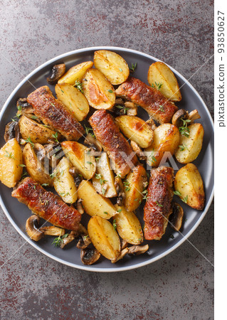 Baked pork rolls with mushrooms and potatoes close-up on the table. Vertical top view 93850627