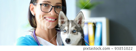 Smiling female veterinarian holding dog in her arms in clinic 93851022