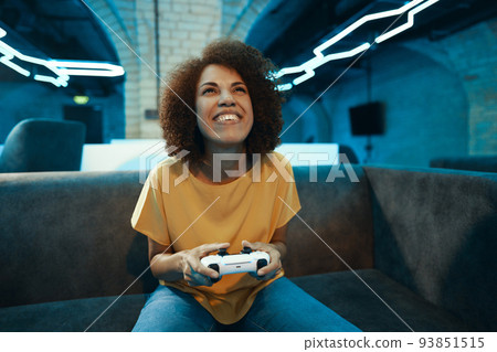 A young woman plays on a console. 93851515