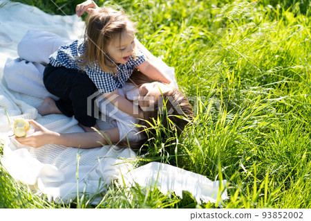 Brother and sister happily hug and laugh, lying on the green grass. The sun is shining, the children are happy carefree. The concept of a happy family life and bonding. Copy space. Brother and sister happily hug and laugh, lying on the green grass. The sun is shining, the children are happy carefree. The concept of a happy family life and bonding. Copy space. 93852002