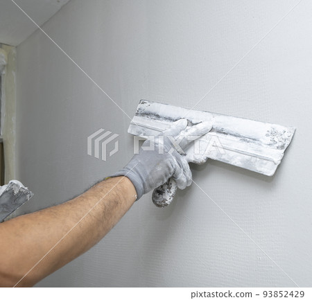Plasterer applies plaster on the wall during repair and restoration work 93852429