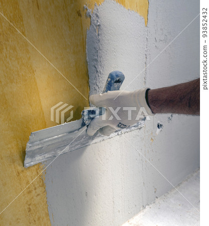 Plasterer applies plaster on the wall during repair and restoration work Plasterer applies plaster on the wall during repair and restoration work 93852432