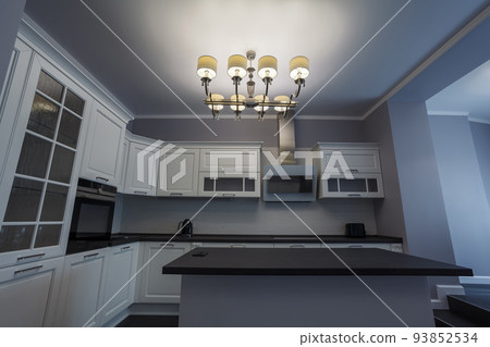 Fashionable kitchen with grey walls and white furniture, a kitchen in a modern classic style with granite countertop and bar island Fashionable kitchen with grey walls and white furniture, a kitchen in a modern classic style with granite countertop and bar island 93852534