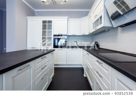 Fashionable kitchen with grey walls and white furniture, a kitchen in a modern classic style with granite countertop and bar island Fashionable kitchen with grey walls and white furniture, a kitchen in a modern classic style with granite countertop and bar island 93852539