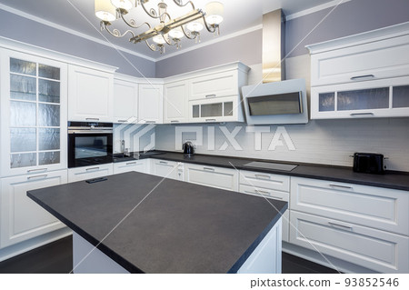 Fashionable kitchen with grey walls and white furniture, a kitchen in a modern classic style with granite countertop and bar island Fashionable kitchen with grey walls and white furniture, a kitchen in a modern classic style with granite countertop and bar island 93852546