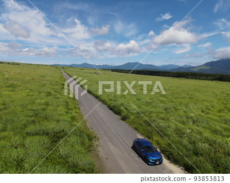 A road and a blue car that stretches diagonally in the blue sky and the meadow with a superb view A road and a blue car that stretches diagonally in the blue sky and the meadow with a superb view 93853813