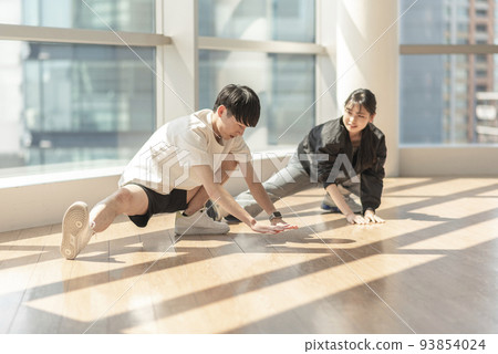 A man stretching while being coached by a trainer A man stretching while being coached by a trainer 93854024
