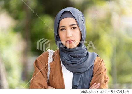 Serious muslim woman in hijab crossing the arms ourdoors Serious muslim woman in hijab crossing the arms ourdoors 93854329