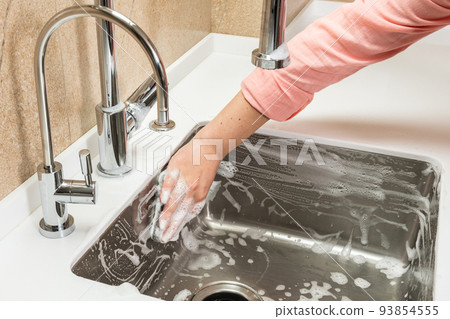 Foam and hand with cleaning sponge on kitchen sink Foam and hand with cleaning sponge on kitchen sink 93854555