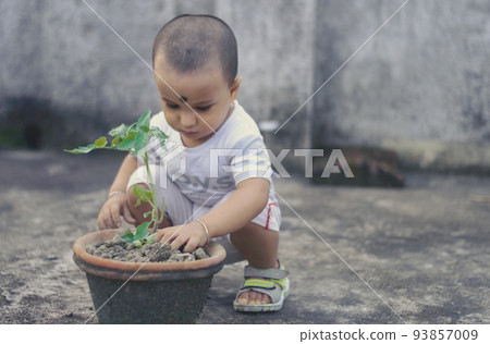Cute Little baby boy with Flower tub loves to play in the dirt. 93857009