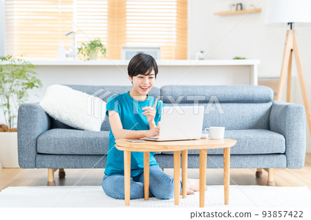 一位女士在客廳裡使用筆記本電腦。 93857422