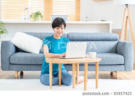 A woman using a laptop in the living room. 93857425