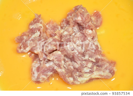 raw chop pork topping in egg yolk for cooking on plate 93857534