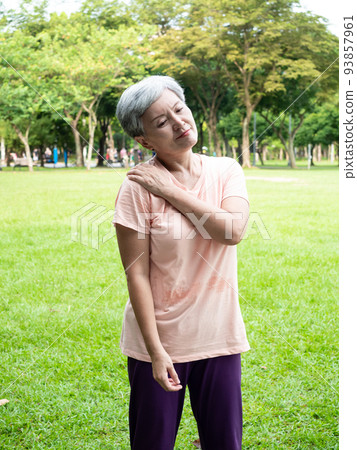 Mature Asian woman in her 60s is uncomfortable with sore shoulders exercising outdoors Mature Asian woman in her 60s is uncomfortable with sore shoulders exercising outdoors 93857961