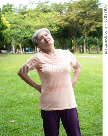 Mature Asian woman in her 60s exercising outdoors feeling uncomfortable with sore back 93857970