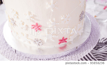 Step by step. Decorating round funfetti cake with pink and white fondant snowflakes. 93858236
