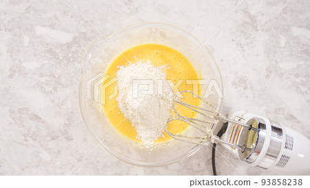 Flat lay. Step by step. Mixing ingredients in a glass mixing bowl to bake funfettti bundt cake. 93858238