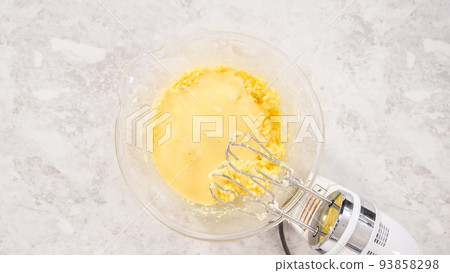 Flat lay. Step by step. Mixing ingredients in a glass mixing bowl to bake funfettti bundt cake. 93858298