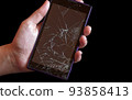 Smartphone with highly broken screen in women hand on black background. 93858413