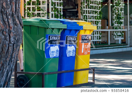 Three recycle containers for glass, plastic and paper on a city street. 93858416