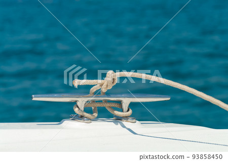 Detail image of yacht rope cleat on sailboat deck. 93858450