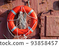 The lifebuoy with cord is hanged on metal wall on the ship. 93858457
