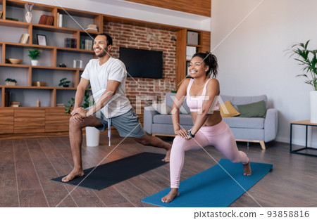 Glad young african american couple athletes in sportswear do exercises or practicing yoga Glad young african american couple athletes in sportswear do exercises or practicing yoga 93858816