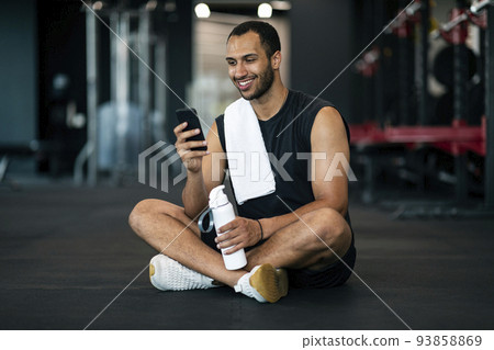 Happy Young Sporty Black Man Resting At Gym With Smartphone And Water 93858869