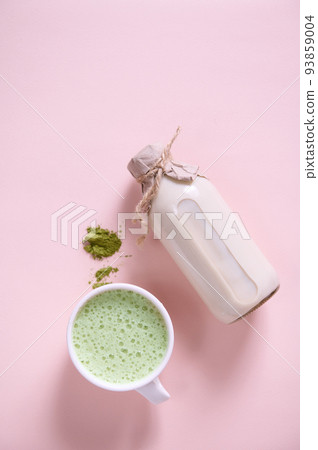 Whipped matcha latte cup, heap of powdered green tea, bottle of healthy organic wholesome raw vegan milk. Flat lay Whipped matcha latte cup, heap of powdered green tea, bottle of healthy organic wholesome raw vegan milk. Flat lay 93859004