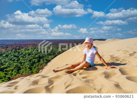 Girl sitting on a huge sand dune, famous tourist destination Dune Pyla. Pilat Dune in France.  93860621