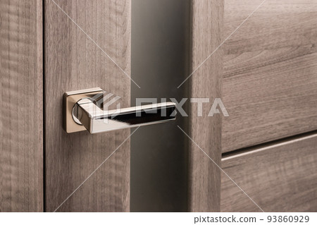 Close up of stylish silver chrome door handle on modern interior door. 93860929