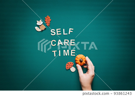 Self-care time word on green background flat lay. Self-care time text wooden letters with body face care products and autumn decor. 93861243