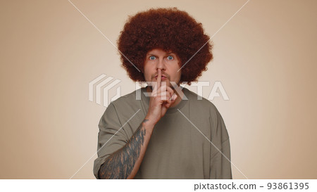 Young man presses index finger to lips makes silence gesture sign do not tells secret, shh be quiet Young man presses index finger to lips makes silence gesture sign do not tells secret, shh be quiet 93861395