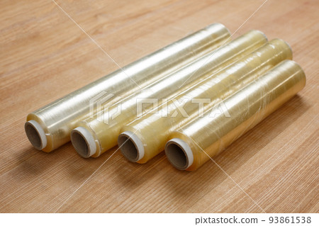 Close up on wooden table lies four rolls of transparent food film on cardboard spool. Close up on wooden table lies four rolls of transparent food film on cardboard spool. 93861538
