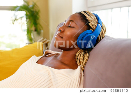 latin hispanic woman listem audio meditate while sitting on sofa in living room 93861540