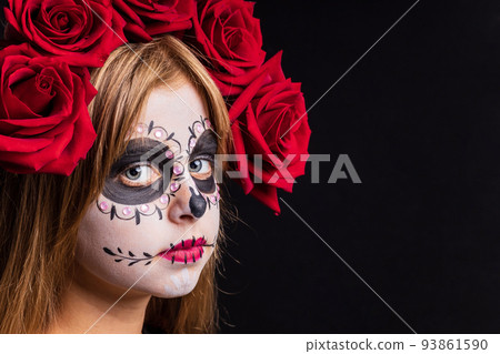 Portrait of young beautiful girl with make-up skeleton on her face and red roses on head 93861590