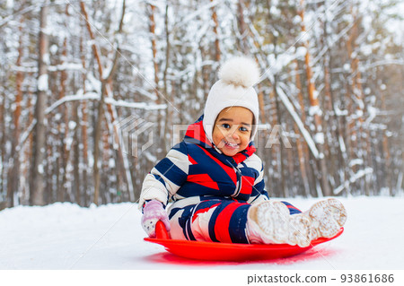 little girl having fun and sledding sled playing in snowy park 93861686